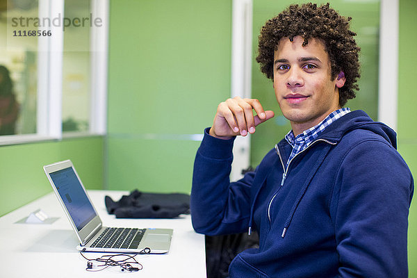 Gemischtrassiger Student benutzt Laptop in der Bibliothek