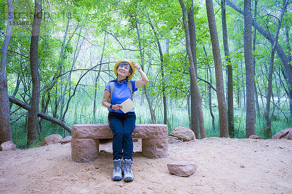 Japanische Frau sitzt auf einer Bank im Park