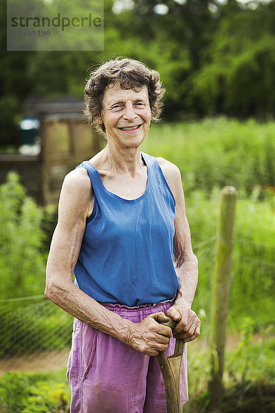 Eine Frau  die auf einem Bauernhof eine Schaufel hält.