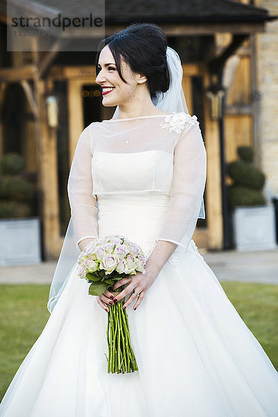 Eine Braut im Brautkleid mit einem Blumenstrauß.