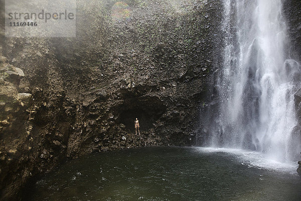 Mixed Race Frau steht in der Nähe von Wasserfall Pool