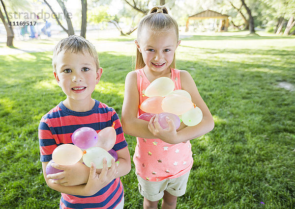 Kaukasischer Bruder und Schwester halten Wasserballons