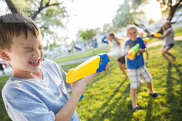 Kaukasische Jungen und Mädchen spielen mit Spritzpistolen