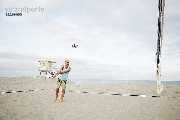 Reifer Mann  der am Strand steht und Beach-Volleyball spielt.