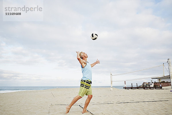 Reifer Mann  der am Strand steht und Beach-Volleyball spielt.