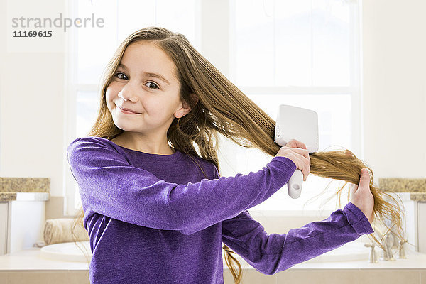 Kaukasisches Mädchen beim Bürsten der Haare im Badezimmer