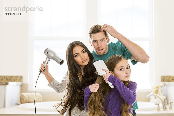 Familie pflegt Haare im Badezimmer