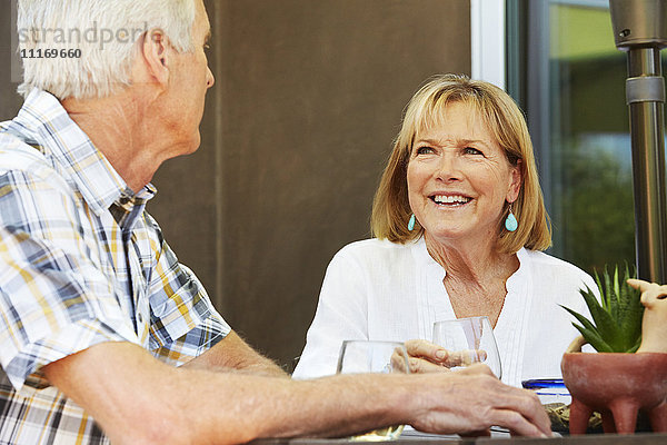 Lächelnde ältere Frau und Mann sitzen im Freien.