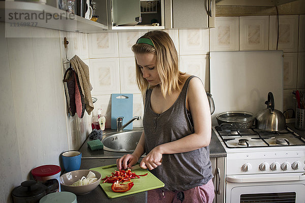 Kaukasische Frau schneidet rote Paprika in der Küche