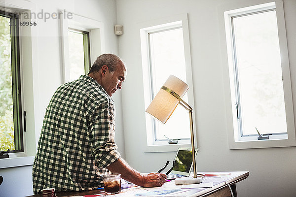 Ein Mann zu Hause mit einem Laptop auf einem Schreibtisch.