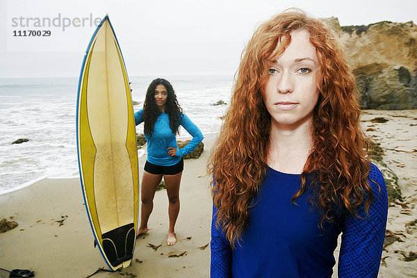 Seriöse Frauen halten Surfbretter am Strand