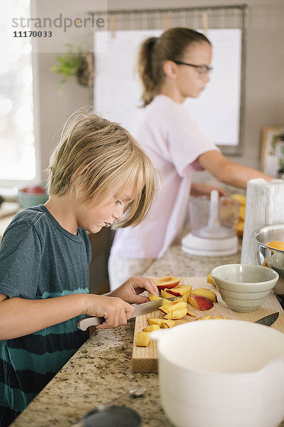 Familie bereitet das Frühstück in einer Küche vor  Junge schneidet Obst.