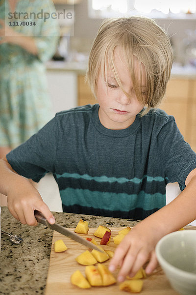 Familie bereitet das Frühstück in einer Küche vor  Junge schneidet Obst.