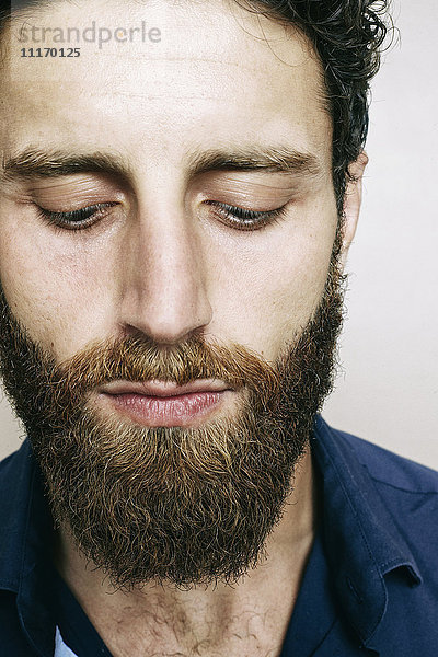 Kaukasischer Mann mit Bart schaut nach unten