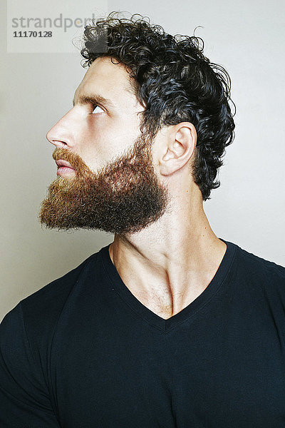 Neugieriger kaukasischer Mann mit Bart schaut auf