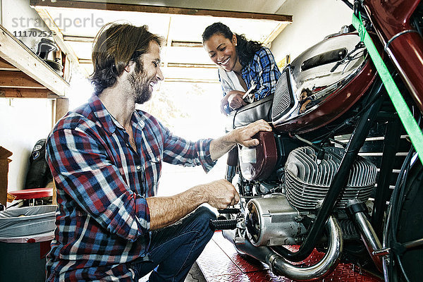 Frau beobachtet Mann bei der Reparatur eines Motorrads in der Garage