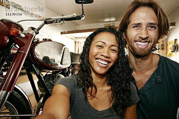 Mann und Frau posieren für ein Selfie mit Motorrad in der Garage