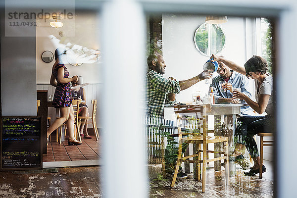 Blick durch ein Fenster in ein Cafe  Menschen sitzen an Tischen.