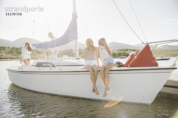 Zwei blonde Schwestern sitzen auf einem Segelboot.