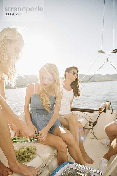 Mutter und ihre beiden blonden Töchter sitzen auf einem Segelboot.