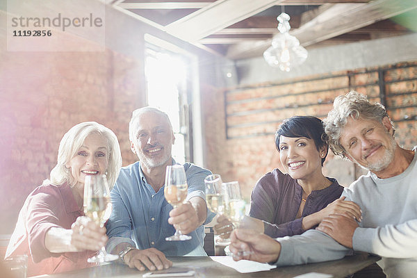 Portrait lächelnde Paare stoßen mit Weißweingläsern am Restauranttisch an