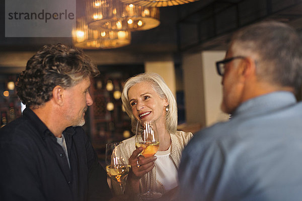 Freunde unterhalten sich und trinken Weißwein in einer Bar