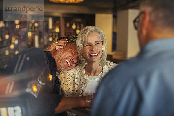 Zärtliches älteres Paar lachend und umarmend in einer Bar