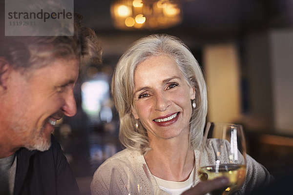 Portrait lächelndes älteres Paar trinkt Weißwein in einer Bar