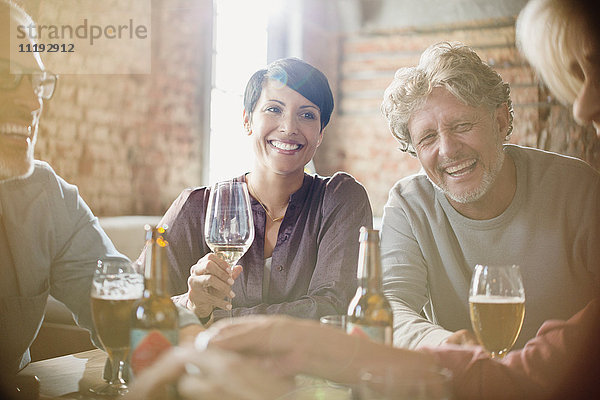 Lachende Paare  die am Restauranttisch Weißwein und Bier trinken