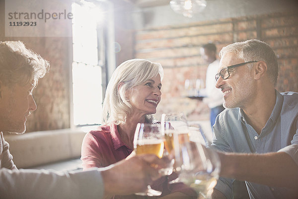 Lächelnde Freunde stoßen mit Bier- und Weingläsern im Restaurant an