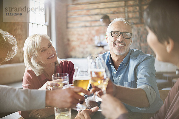 Paare stoßen mit Bier- und Weingläsern am Restauranttisch an
