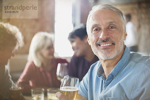 Porträt eines selbstbewussten Mannes  der mit Freunden am Restauranttisch Weißwein trinkt