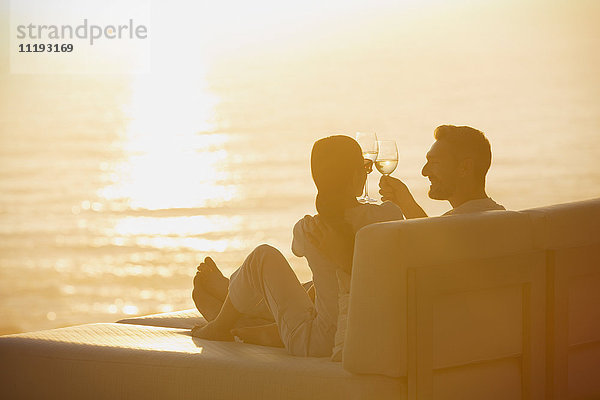 Silhouette Paar Toasting Weingläser auf Liegestuhl mit Sonnenuntergang Blick aufs Meer