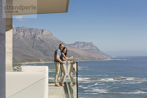 Paar mit Blick auf sonnigen Meerblick vom Luxusbalkon