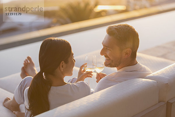 Paar entspannt Toasting Weißwein Gläser auf Chaiselongue auf Luxus-Terrasse