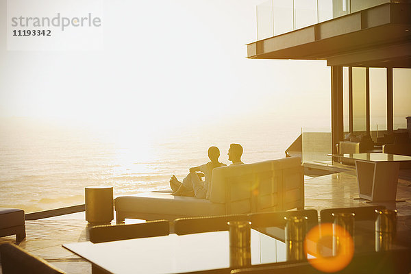 Silhouette Paar entspannt auf Chaiselongue genießen Sonnenuntergang Meerblick