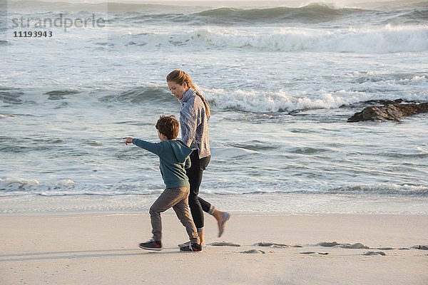 Glückliche Mutter und Sohn  die am Strand spazieren gehen.