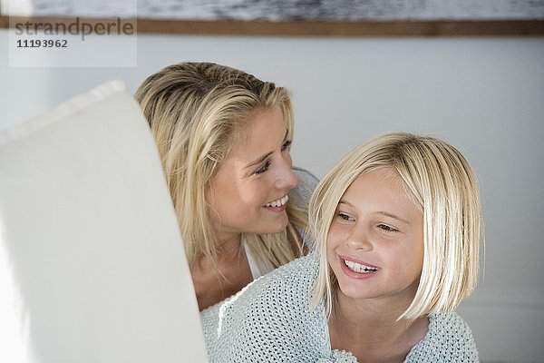 Glückliche Mutter und Tochter lächelnd im Wohnzimmer
