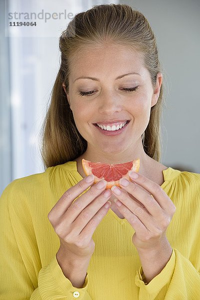 Nahaufnahme einer fröhlich schönen Frau beim Grapefruitessen
