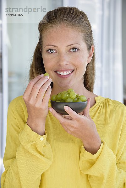 Porträt einer fröhlich schönen Frau beim Traubenessen
