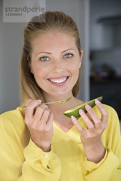 Porträt einer fröhlich schönen Frau beim Essen von Avocado