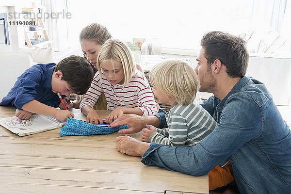 Eltern und Kinder bei den Hausaufgaben auf dem Tisch