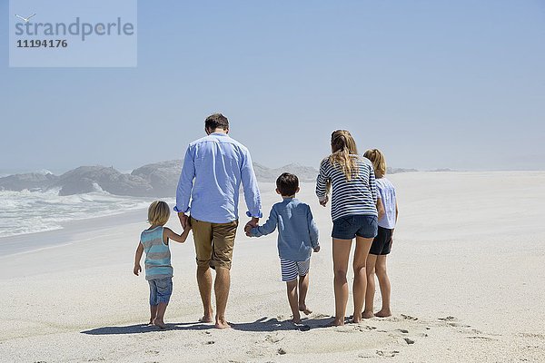 Rückansicht einer fünfköpfigen Familie beim Spaziergang am Strand
