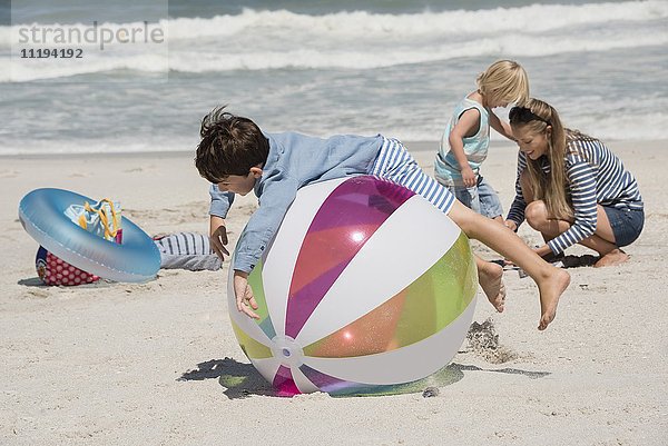 Frau mit ihren beiden Kindern beim Spielen am Strand