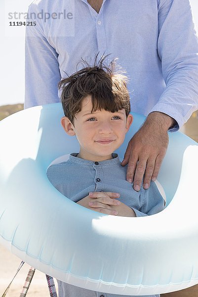 Glücklicher Vater und Sohn mit Gummiring am Strand