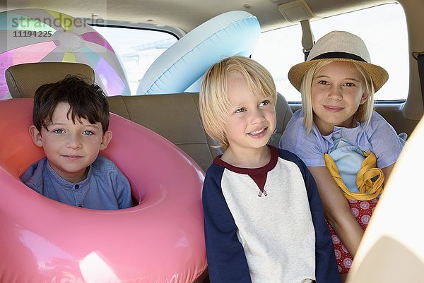 Glückliche Kinder im Auto mit Strandkleidung für den Urlaub