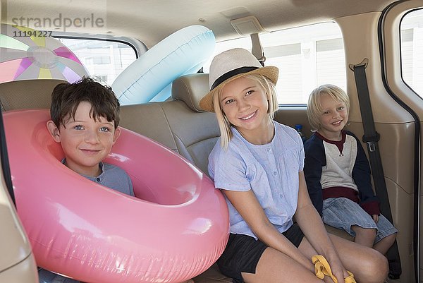 Glückliche Kinder im Auto mit Strandkleidung für den Urlaub