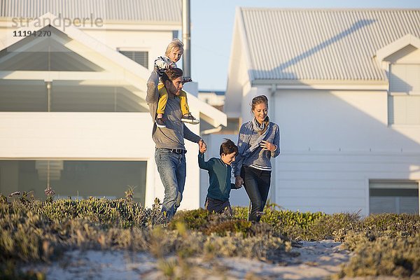 Glückliche Familie beim Spaziergang vor einem Haus