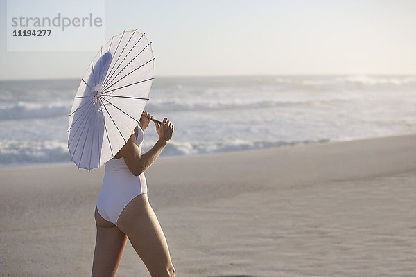 Frau mit Sonnenschirm am Strand