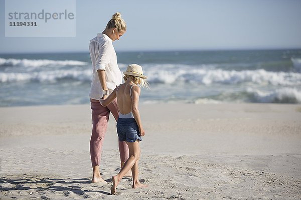 Profil einer Frau mit ihrer Tochter  die am Strand spazieren geht